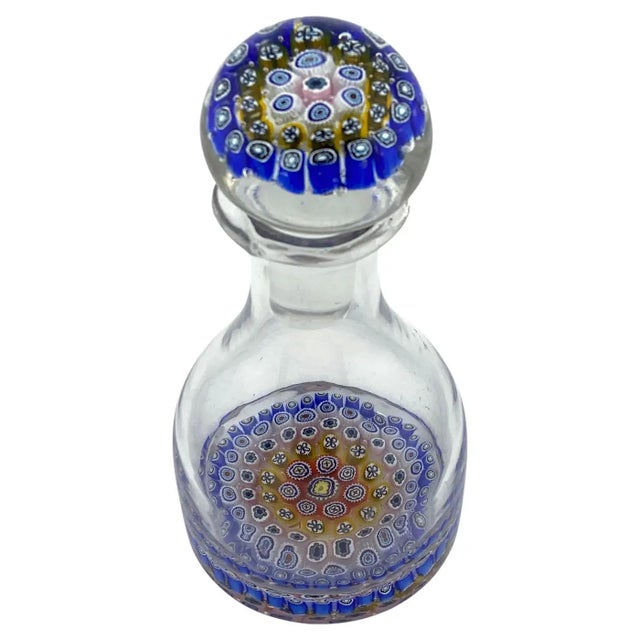 This is a hand blown art glass perfume bottle with stopper. The clear heavy glass body has a layer of millefiori...
