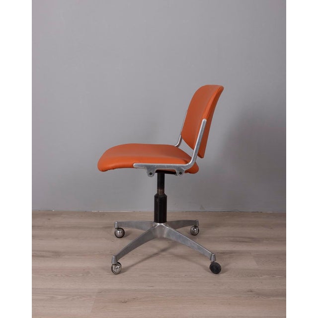 Swivel chair with wheels, chromed metal frame and orange leather upholstery, model "DSC 106" designed by Giancarlo Piretti...