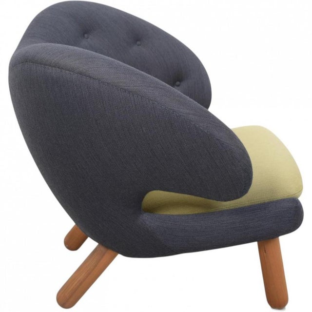 Finn Juhl Pelikan chair upholstered in grey and green fabric, and with legs of walnut. The chair is from around 2016 and...