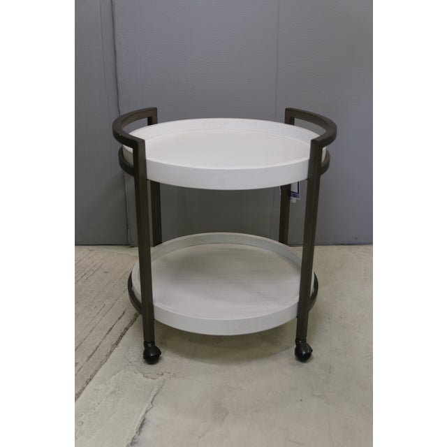 The oval Osprey end table is a distinctive design, with two stationary gallery trays and a metal frame on casters in a...
