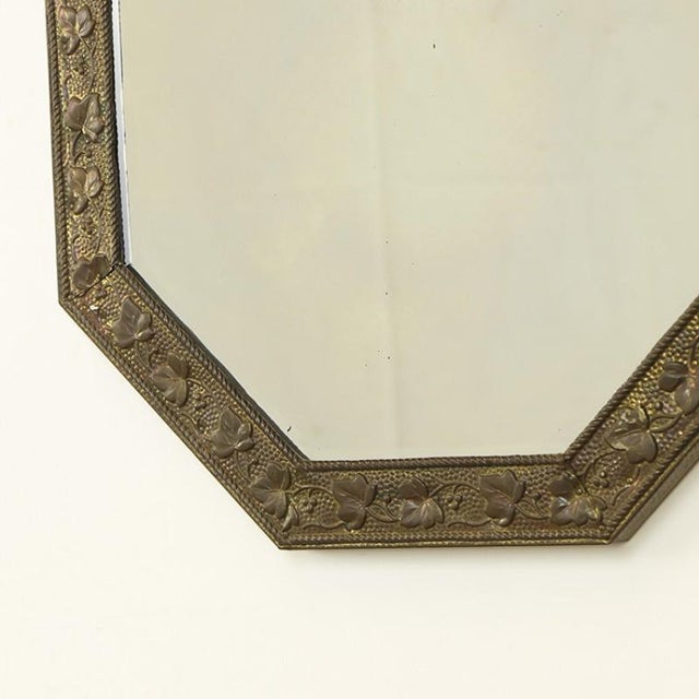 Decorative octagonal mirror with a brass frame. This mirror features faceted glass and hangs from a decorative chain. It...
