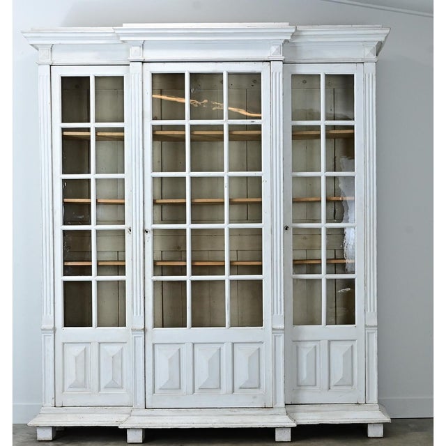 A large 19th century French pine bibliotheque with its original white paint. The cornice juts out sharply from atop four...