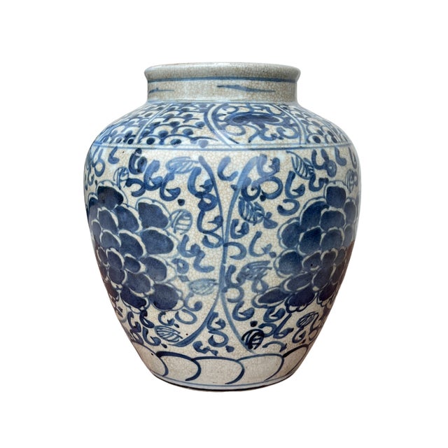 This blue and white vase is adorned with bold peony-style blooms and flowing vine motifs, all hand-painted with rich...