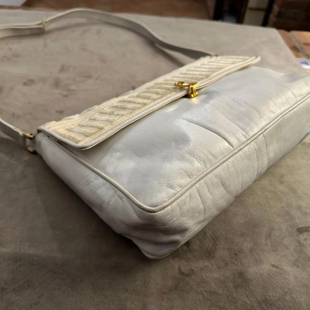 Crafted from soft white leather, giving it a classic and sophisticated look. The flap features a textured design with...