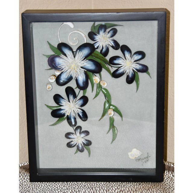 Black wood shadow box with a collection of shells formed into a floral art piece under glass. Hanging hooks on reverse....