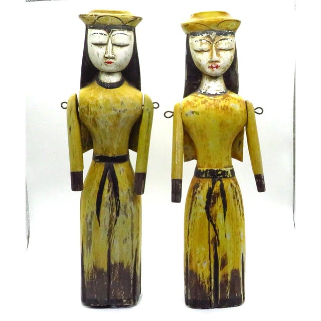 A unique pair of hand-carved and painted Santos-style figurines of nuns. Each figure is wearing a yellow habit and cap,...