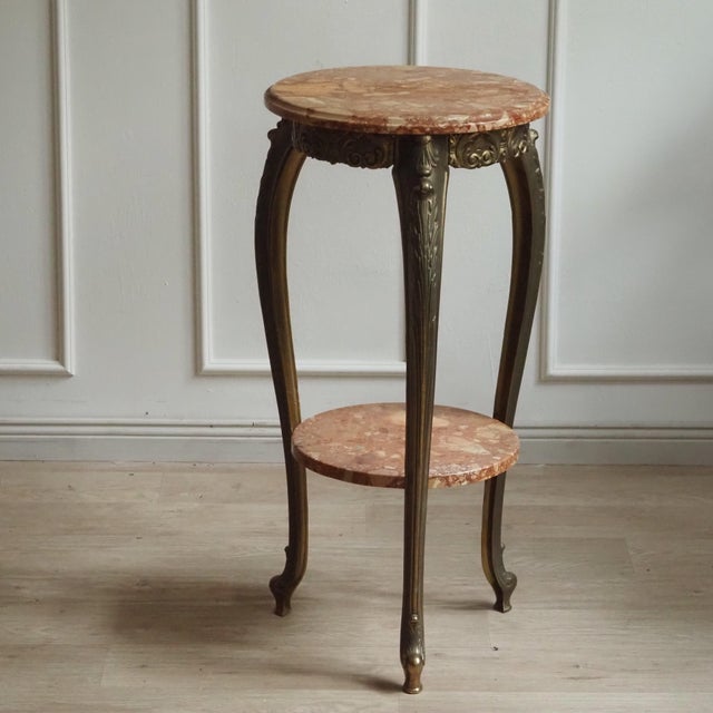 This two-tiered gueridon in the Louis XV style combines cast brass legs with reddish-veined marble and stylistically dates...