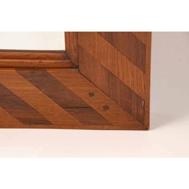 The rectangular beveled mirror plate set within a conforming surround inlaid with contrasting strips of oak and mahogany...