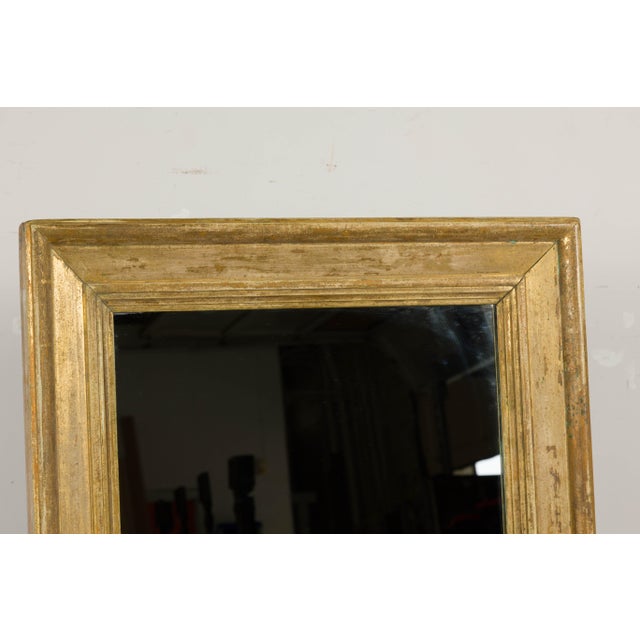 A French rectangular mirror from the 19th century painted with distressed golden tones and with molded accents. Embodying...