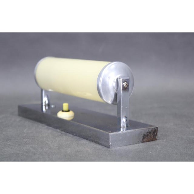 A 1930s bauhaus tubular wall light produced in czechoslovakia, constructed with a chrome-plated metal frame and a cream...