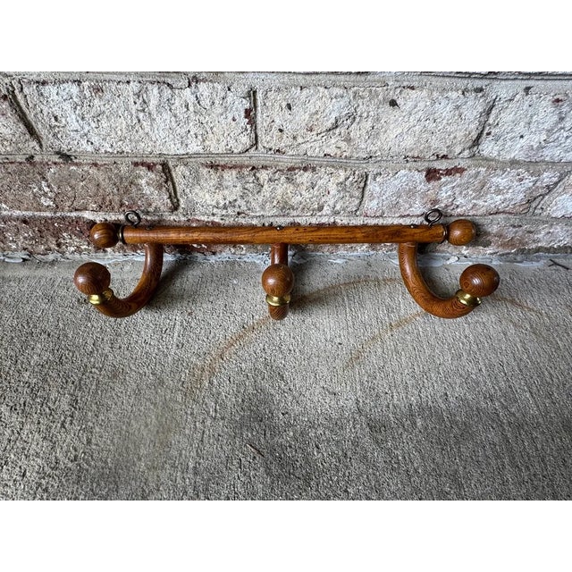 Vintage wall hanging coat rack, early American. Made of wood and brass, this piece has three (3) adjustable hooks that are...