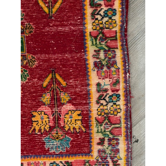 Small handmade accent rug with a central geometric medallion and floral border in deep red, green, cream, pink, and blue...