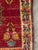 Small handmade accent rug with a central geometric medallion and floral border in deep red, green, cream, pink, and blue...