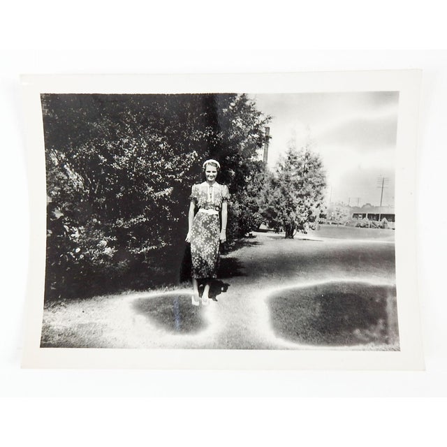 1930's snapshot photograph of young woman in her Sunday best standing on portal looking overexposure holes. Unframed.