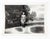 1930's snapshot photograph of young woman in her Sunday best standing on portal looking overexposure holes. Unframed.