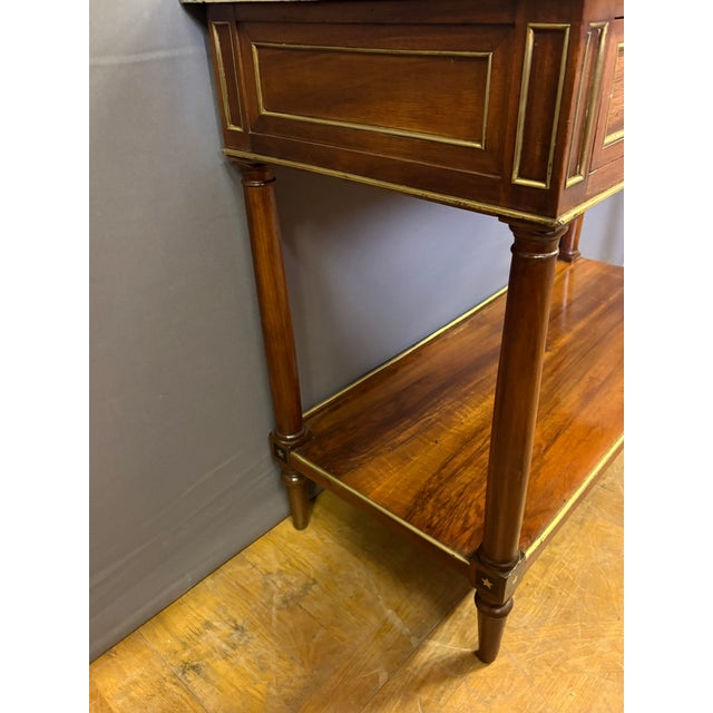 A Directoire period console table in walnut with brass trim, featuring a drawer, marquetry star decoration, and a light...
