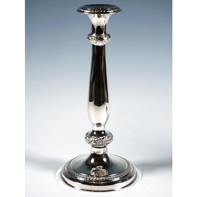 Two festive Biedermeier silver candlesticks on a stepped, curved base featuring a chased decorative band with small...