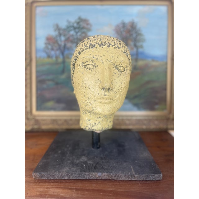 This vintage papier-mache head sculpture presents a compelling blend of primitive styling and mid-century modern display...