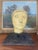 This vintage papier-mache head sculpture presents a compelling blend of primitive styling and mid-century modern display...
