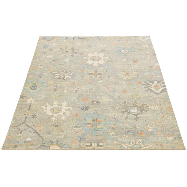 Hand-knotted modern Oushak style wool rug featuring a serene palette of beige, blue, and terracotta. Inspired by...