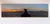 This artwork depicts a figure silhouetted against a sweeping sunset, overlooking a sprawling industrial landscape. The...