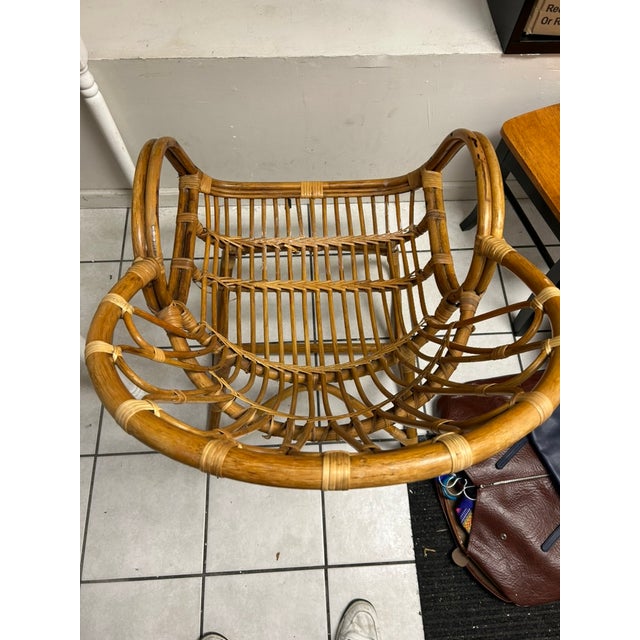Striking vintage bent rattan lounge chair featuring a sculptural barrel silhouette with dramatic looping armrests and...