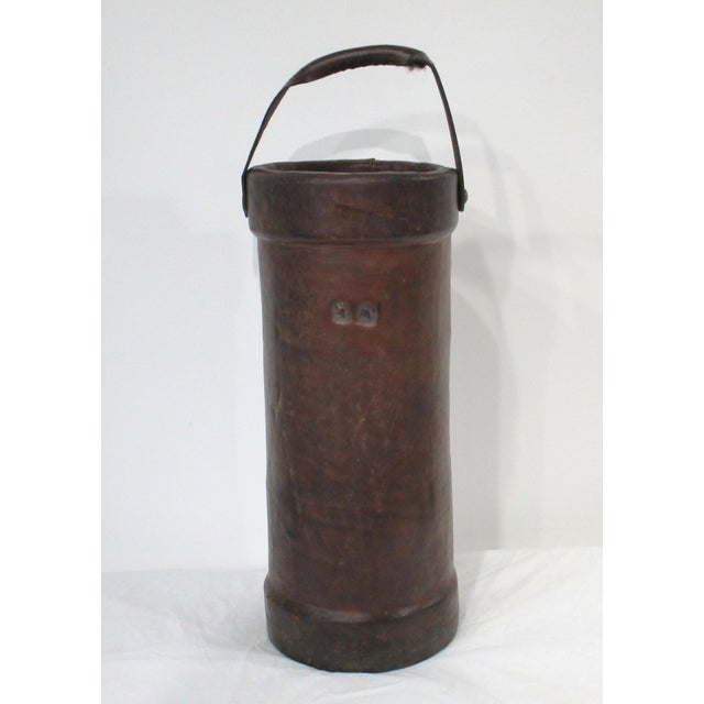 A vintage British thick leather fire / power bucket used today as a great umbrella stand or cane holder . With heavy strap...