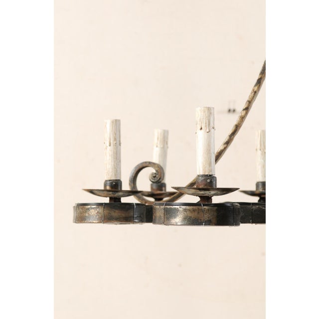 A French mid 20th century suspended eight-light forged-iron chandelier. This vintage French chandelier features a central...