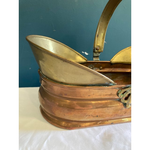 This beautifully aged vintage brass and copper handled basket is a striking example of functional antique design....