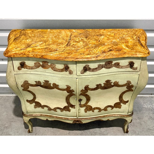 A refined Italian Rococo Revival commode dating to the late 19th century, featuring a graceful bombe-form case with...