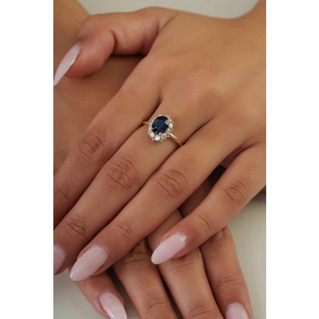 This halo cocktail ring features a 1.55 carat natural blue sapphire, set in 14k yellow gold. The center stone measuring...