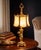 Stunning vintage Hollywood Regency table lamp featuring an ornate brass cherub base and original slag glass panel shade....