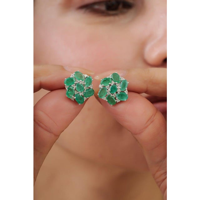 These elegant 6.21 carat emerald and diamond floral cluster stud earrings are crafted in 925 sterling silver and feature...