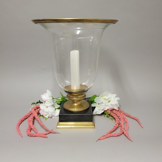 Elegant and substantial, this hurricane lamp features a bell-shaped glass globe with a brass rim, set on a solid black...