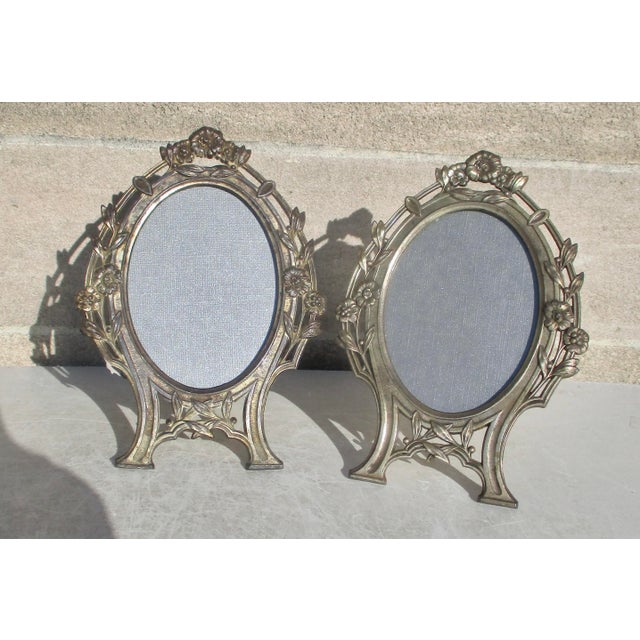Spelter Metal oval frames with glass faces. Surrounded by floral clusters and climbing vines. Marked on the back: MADE IN...