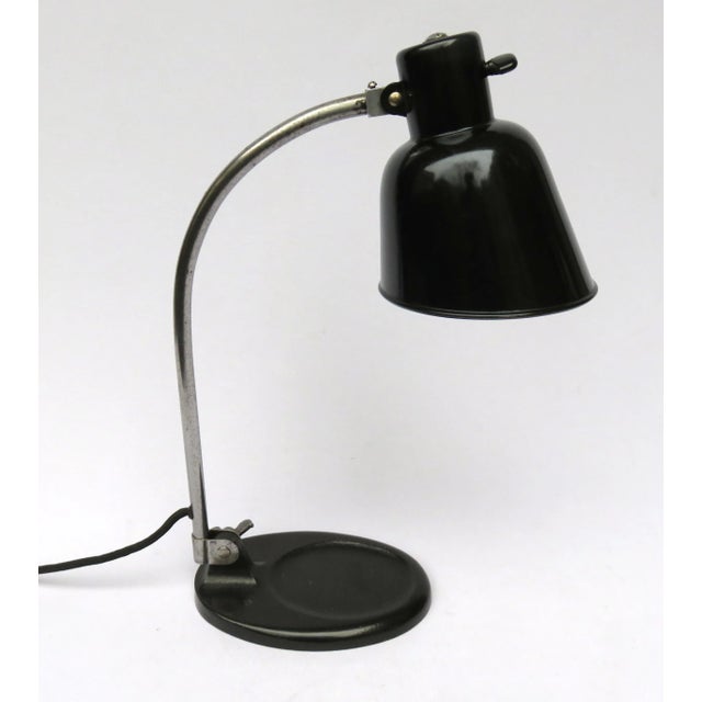 This work lamp features a steel arm, a black-coated heavy base, and a shade with original silver paint inside. It has a...
