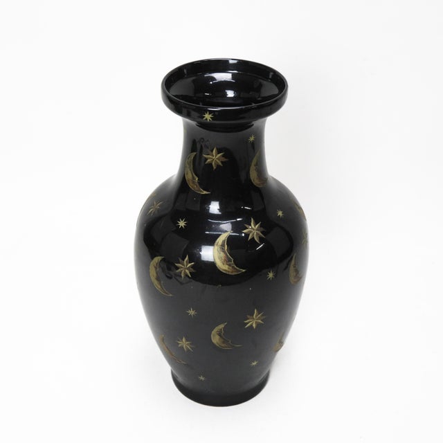 This striking black ceramic vase showcases an enchanting celestial design, featuring hand-painted gold crescent moons and...