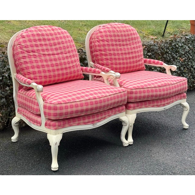 Charming pair of Bergere chairs with a distressed white-painted wooden frame featuring elegant, curved legs and scrolled...