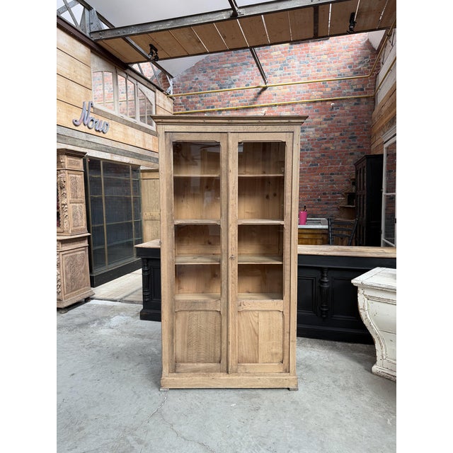 This antique raw oak display cabinet has been fully restored. It consists of two glass doors at the top, which lock and...