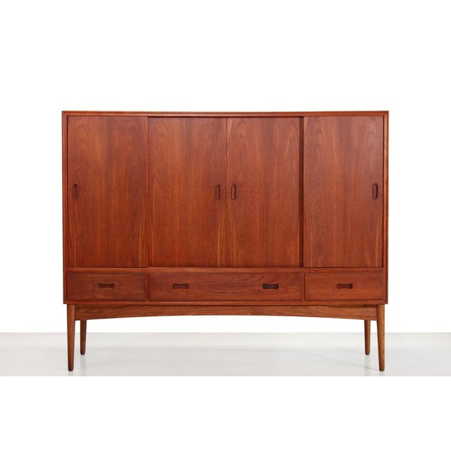 Vintage teak Danish design highboard. This cabinet is made of teak and has an oak base. The cabinet has four sliding doors...