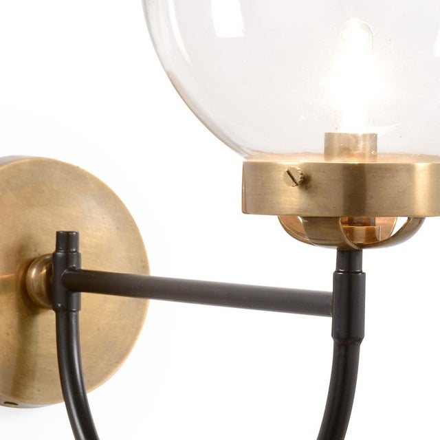 Featuring two toned metal and a glass orb, the bistro sconce has a modern feel. A black arm connects the brass base and...