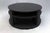 Circular wooden coffee table with black color finish. Middle shelf and a bottom shelf low to the ground.