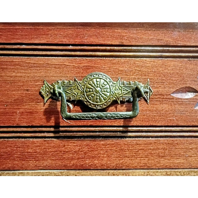 This Eastlake chest of drawers reflects the decorative arts movement popular in the late 19th century, characterized by...
