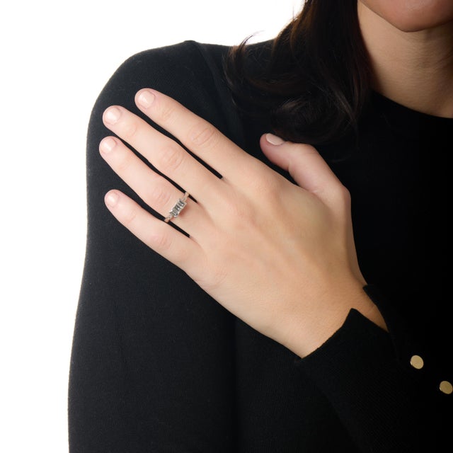 This elegant Art Deco engagement ring is a refined celebration of symmetry, geometry, and timeless design. At its center,...