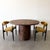 A striking 1970s Mid-Century Modern round dining table featuring richly figured burlwood veneer and a sculptural pedestal...