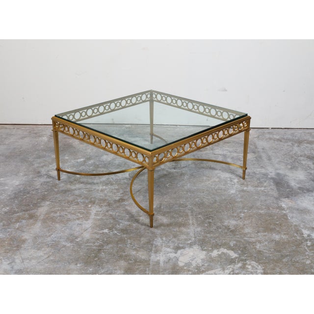 An Italian gilt bronze coffee table from the mid 20th century, with glass top and ring motifs. Created in Italy during the...