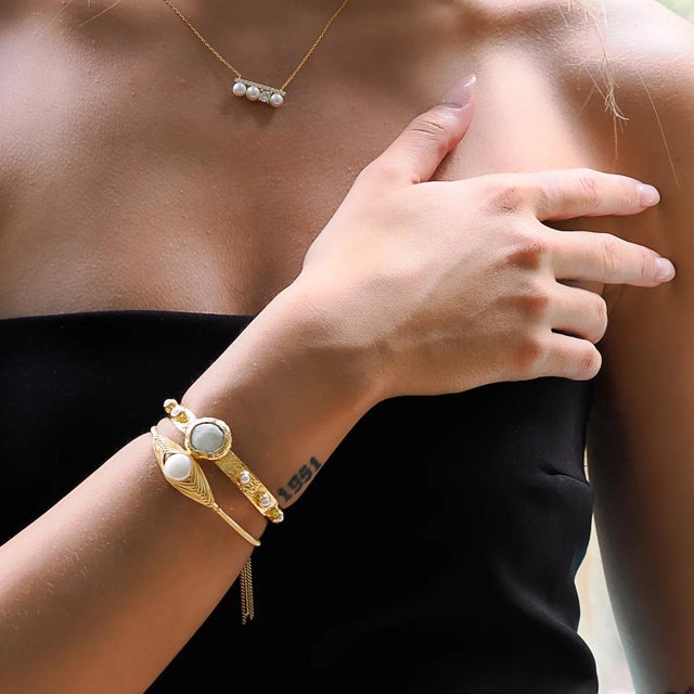 The Cleopatra Gold & Pearl Tassel Cuff Bracelet is a true celebration of femininity and grace, inspired by the timeless...