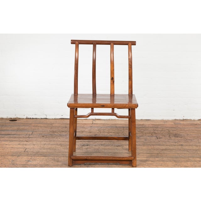 A Chinese late Qing Dynasty period chair from the early 20th century with vertical slats, pierced apron, pillar strut...