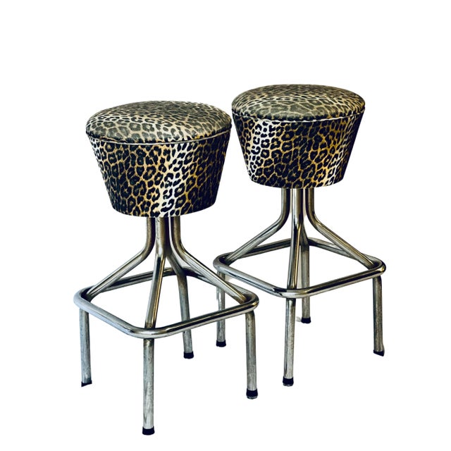 Stylish pair of vintage chrome swivel bar stools in faux leopard Naugahyde. The stools feature original fabric with...