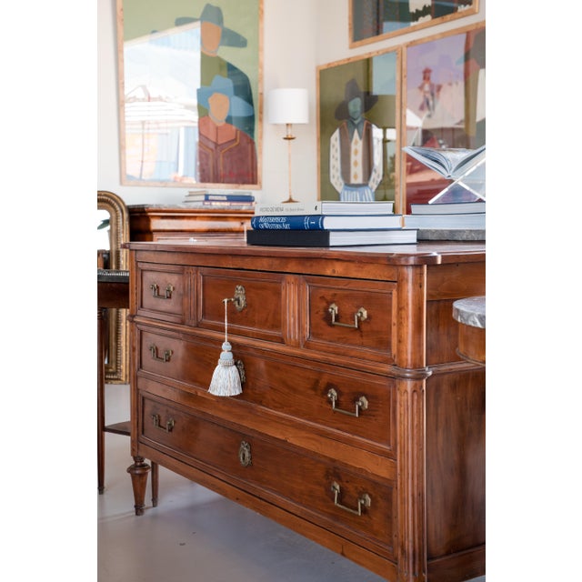 A beautifully crafted French Louis XVI style three-drawer commode, distinguished by elegant fluted pilasters, tapered...